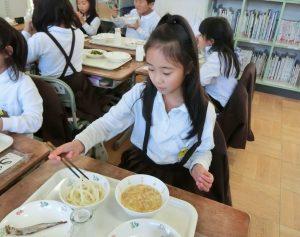 子供がめんをおはしで食べている写真