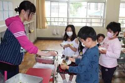 先生に給食を追加盛りしてもらう小学2年生