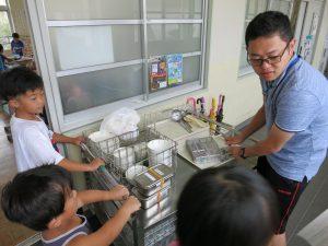 配膳員さんと子供たちが食器を方付けている写真