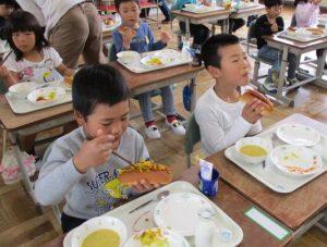 子供たちがコッペパンは切り目入りで、ウインナーやキャベツをはさんで食べている写真