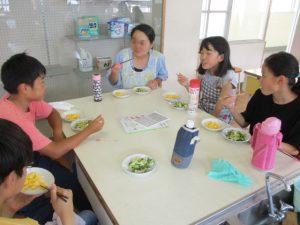 皆さんが座って、話しながら、料理を食べている写真