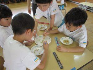子供達はマイ箸を使って、お豆つかみゲームをしている写真1