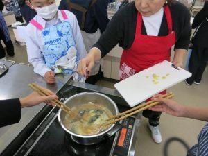 鍋にしょうがを入れる生徒たちの写真