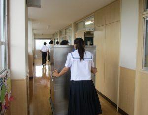 女の人はコンテナを教室近くまで運んでいる写真