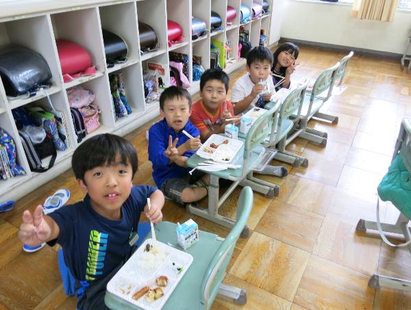 床に座り、いすを食卓にして食べる、千早小吹台小3年生