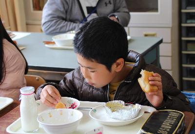 手づくりいちごジャムをパンにつけて食べる小学6年生