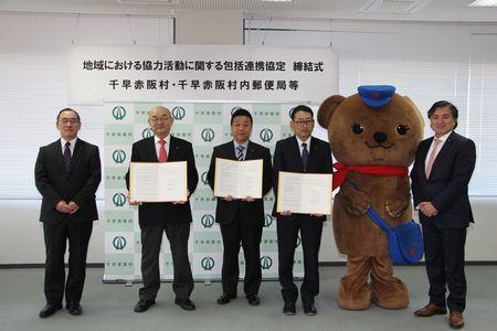 男性5人と熊の着ぐるみが並んで立ち記念写真を撮っている写真