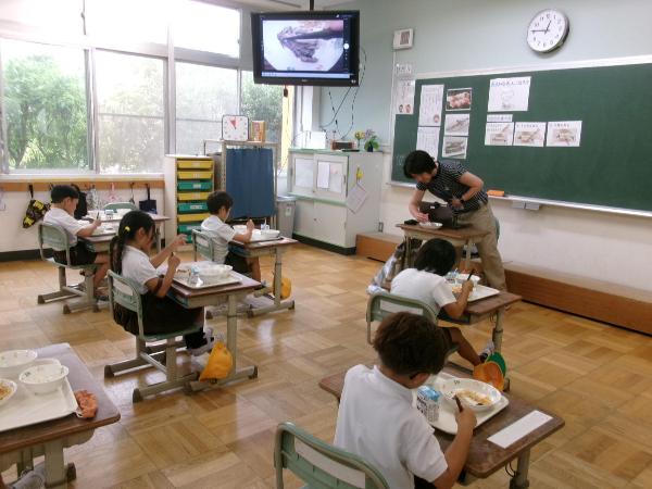 モニターを見ながら、魚に箸を入れてみる赤阪小学校1年生