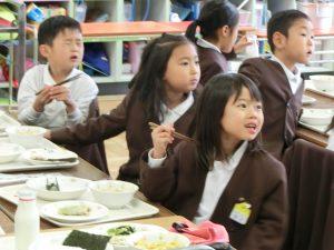給食を食べながら手洗いクイズを考える生徒の写真
