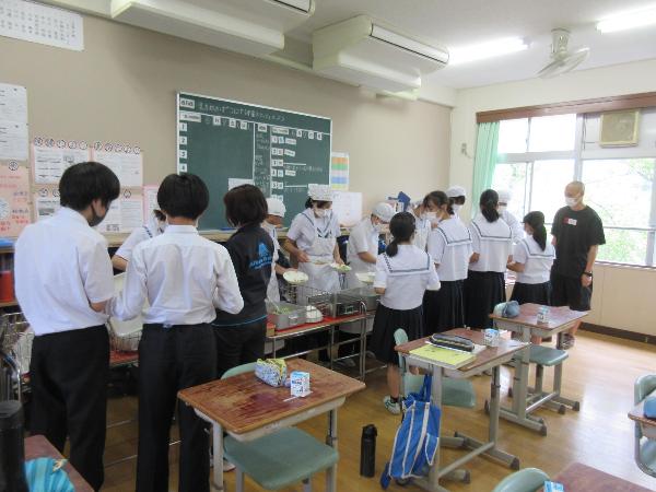 赤い配膳台を2台使用して配膳をする村立中学校3年生