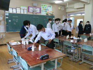 学生全員マスクをして、布巾で机を拭いている写真