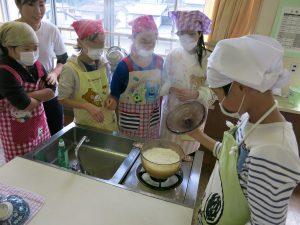 炊き上がったご飯の鍋の蓋を開ける生徒たちの写真