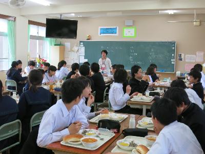 給食を食べながら栄養教諭の話を聞く中学2年生