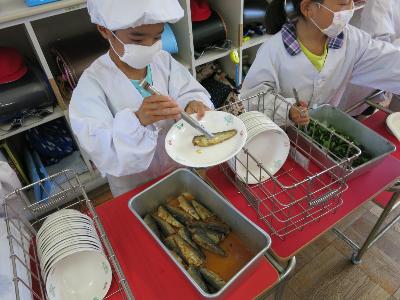 いわしの梅煮を配膳する小学1年生