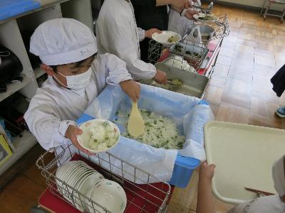 えんどう豆ごはんを配膳する小学3年生