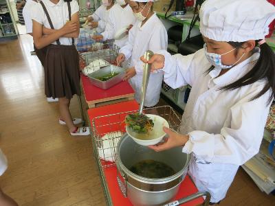 貝杓子を使って上手に配缶する小学4年生