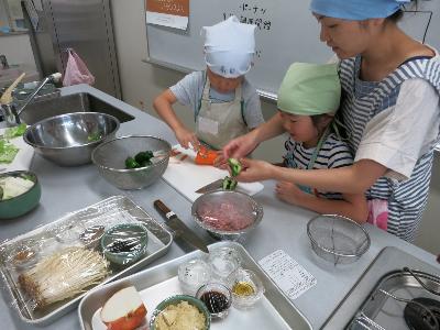 保護者と野菜を切る小学生