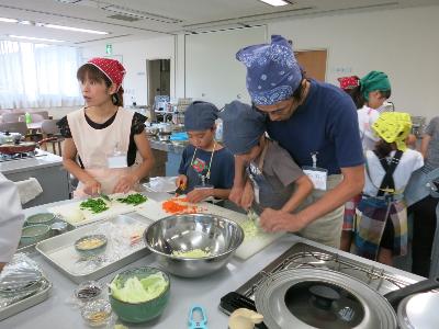 保護者の方と一緒に野菜を切る小学生