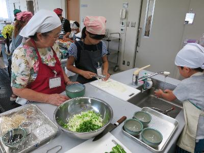 保護者と野菜を切る小学生