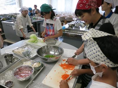 保護者と野菜を切る小学生