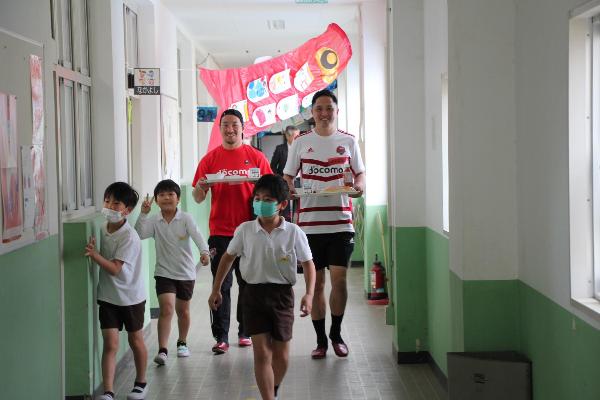 給食を持って廊下を移動するラグビー選手