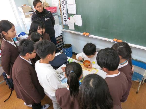 豆つかみゲームをする男子を見守る赤阪小学校4年生