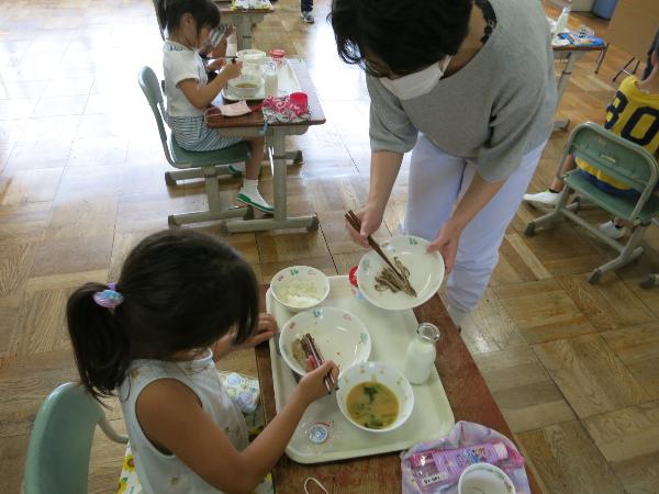 上手な食べ方の見本を見せてもらう小学1年生