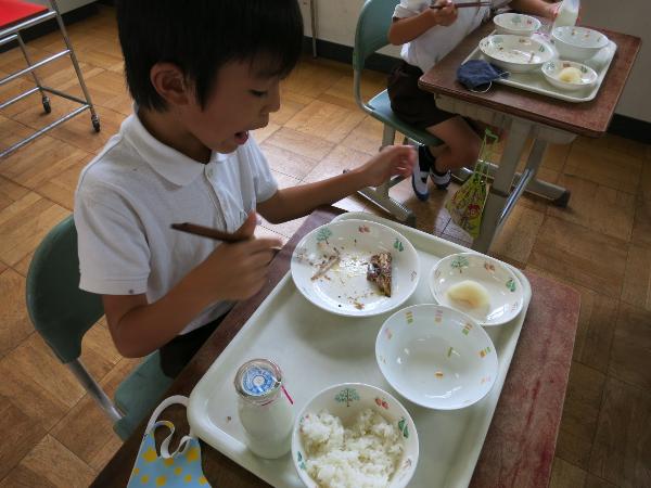 がんばっていわしの梅煮を食べる赤阪小学校2年生