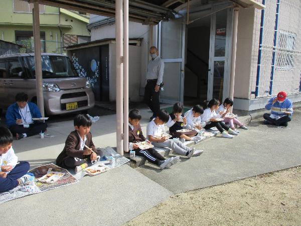 外で弁当給食を食べる赤阪小学校の子ども達
