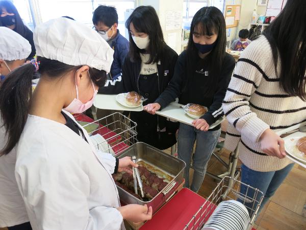 和牛100パーセントハンバーグを盛り付けてもらう千早小吹台小学校5年生