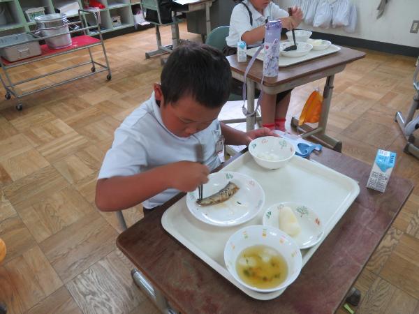 いわしの梅煮におはしを入れる赤阪小学校2年生