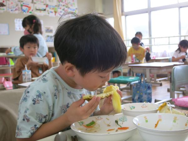 おいしそうにパイナップルを食べる児童