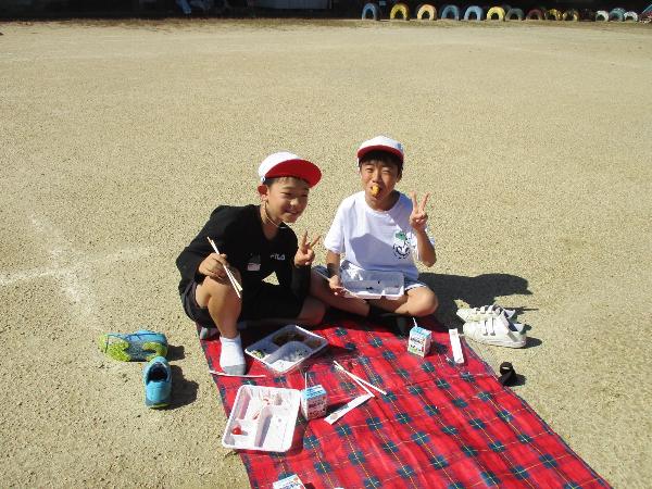 レジャーシートを運動場にしいて食べる千早小吹台小学校児童