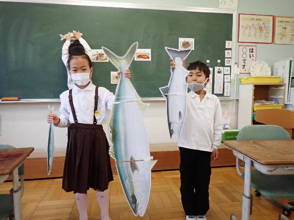 実物大の魚のイラストを持つ赤阪小学校1年生