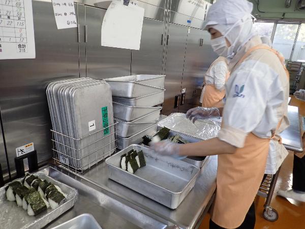 調理員さんがひとつひとつおむすびを握っている写真