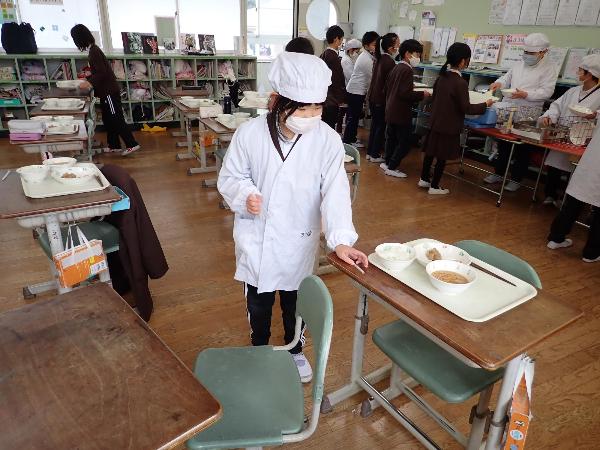 牛乳のストローを机に配る、赤阪小学校の給食当番さん