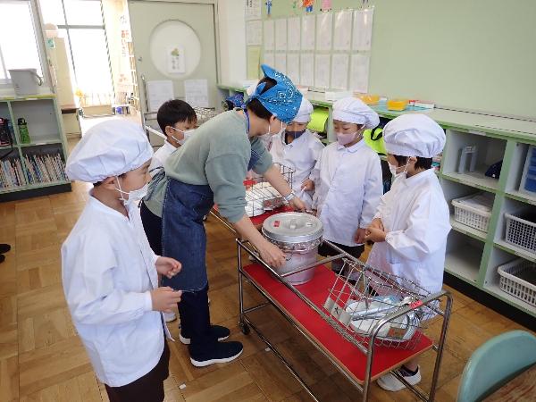 先生に教えてもらいながら配膳をがんばる赤阪小学校1年生