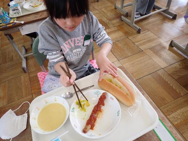 切れ目入りパンにケチャップフランクをはさもうとする千早小吹台小学校1年生