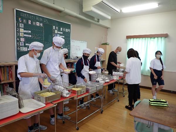 きちんとエプロンと帽子を着て配膳をする村立中学校2年生