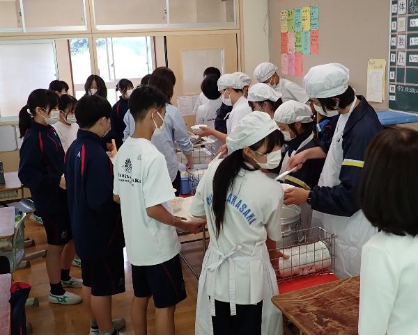 きちんとエプロンと帽子を着て配膳をする村立中学校2年生