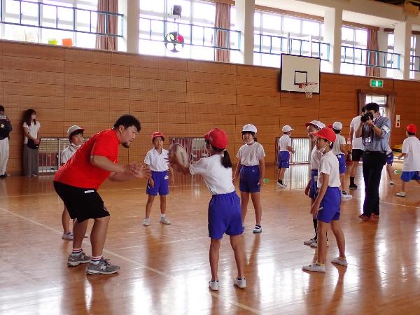 体育館でプロラグビー選手とパスの練習をする赤阪小学校3,4年生