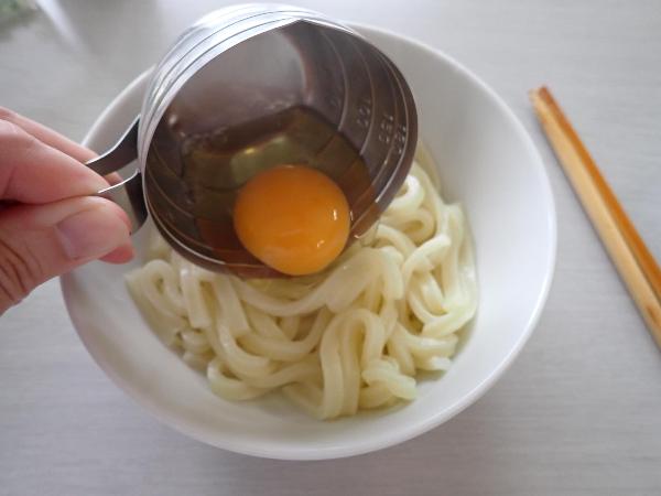 熱いうどんに生卵をのせるところ