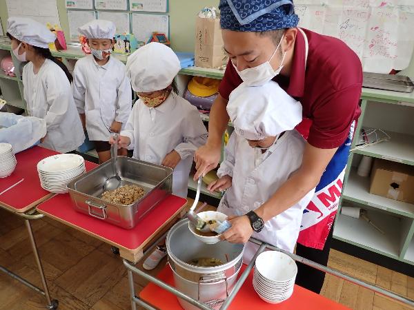 担任の先生に盛り付け方を教えてもらう赤阪小学校2年生