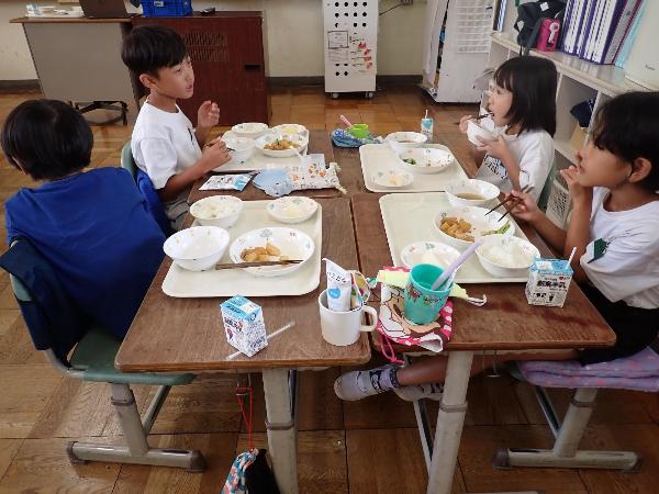 机を向かい合わせの班の形にして楽しそうに給食を食べる千早小吹台小2年生