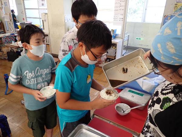 いわしの梅煮の煮汁をごはんにかけてもらう千早小吹台小学校5年生