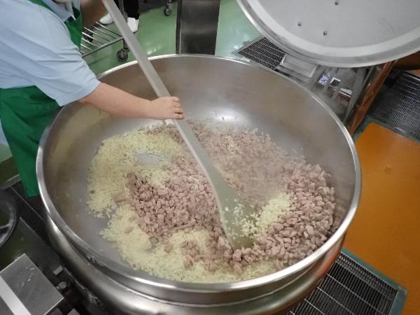 玉ねぎと豚肉を炒める調理員さん