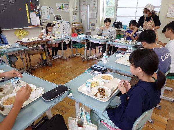 給食を食べ始める6年生と追加盛りをして下さる担任の先生