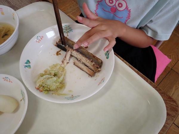 モニターを見ながら魚に箸を入れる千早小吹台小学校1年生