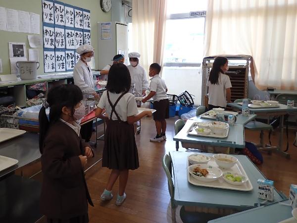 4.5.6年生が給食当番をし、1.2.3年生が配膳をするようす